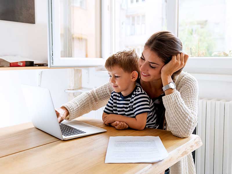 mother and child son at a table with laptop shopping online